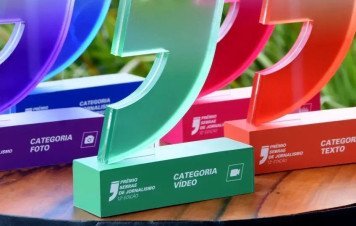 Esta imagem exibe uma coleção de troféus da 12ª Edição do Prêmio Sebrae de Jornalismo, dispostos sobre uma mesa de madeira.
